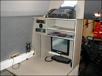 Vnitřní část vozu (po směru jízdy) - pracovní plocha s monitorem a klávesnicí, telefonem/faxem, anal