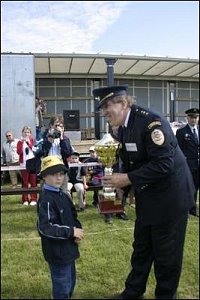 Nejmladší účastník závodu předává putovní pohár po roce „držení“ hasiči z Volče zpátky do rukou ředi