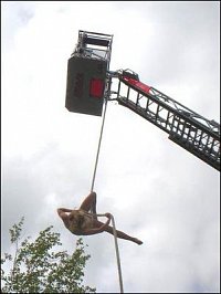 Sličná akrobatka zavěšená na laně žebříku Metz v expozici firmy Rosenbauer. 